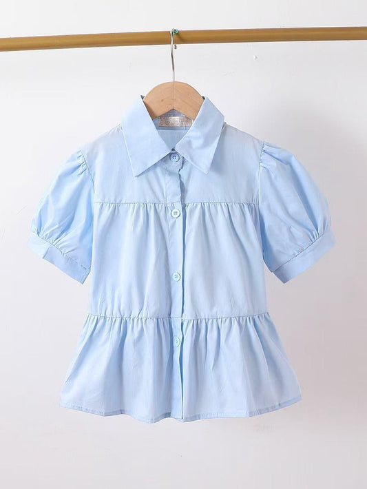 Chemisier bleu à manches courtes pour femme, offrant une coupe moderne et légère, parfait pour un look printanier ou estival.